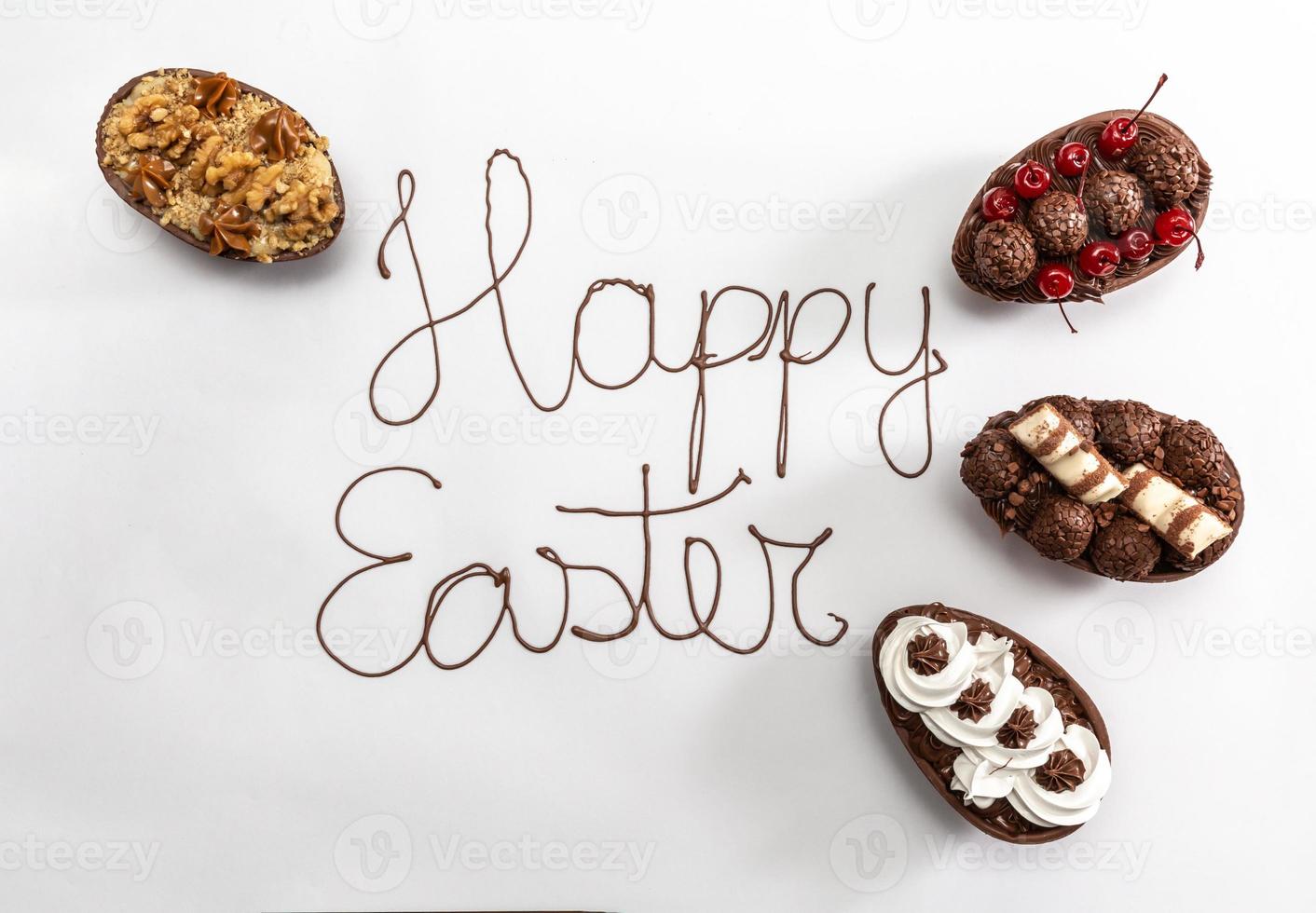 Happy Easter written with melted chocolate on white background. With gourmet Easter eggs decorating on the sides. photo
