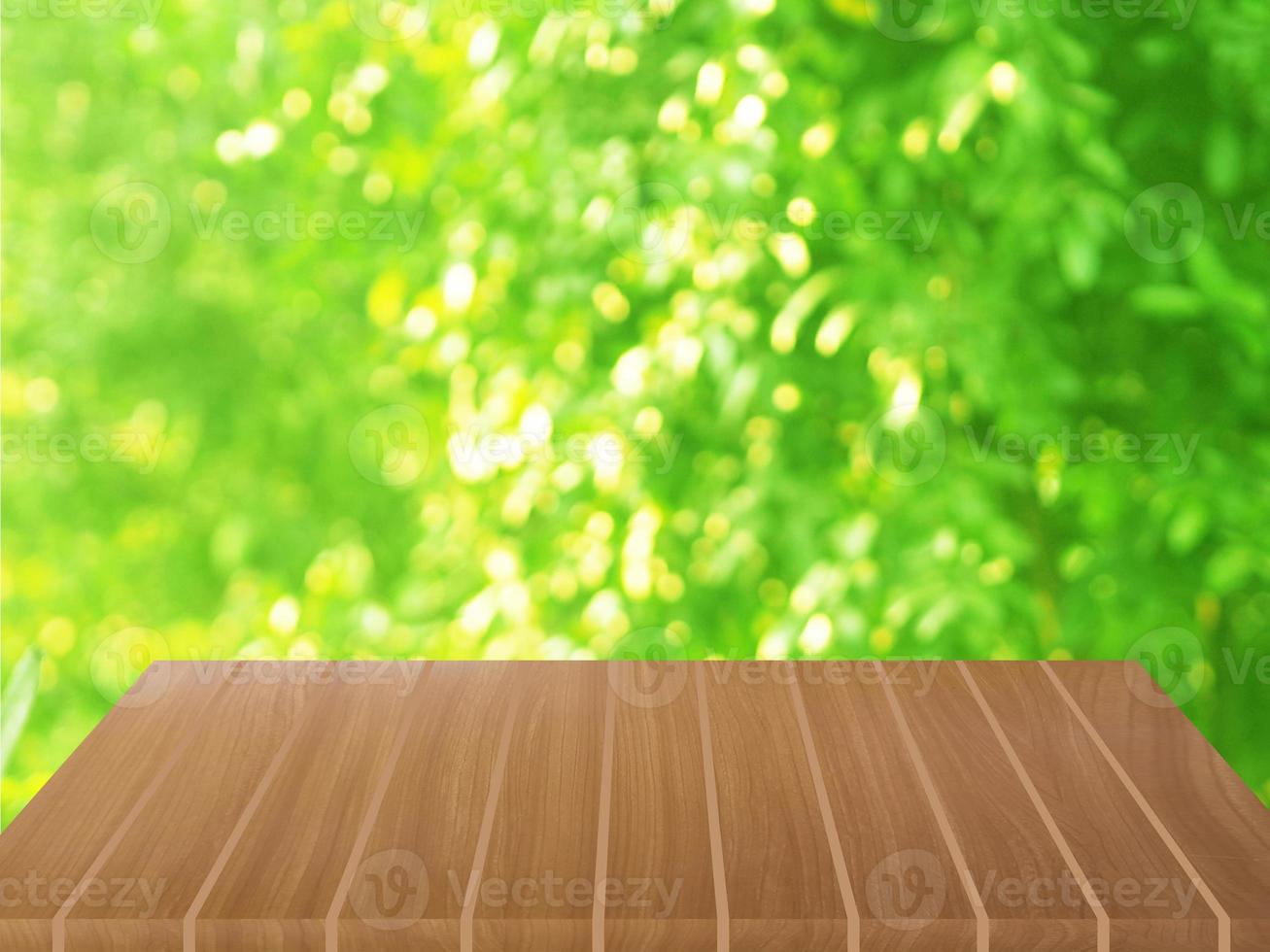 mesa de madera marrón sobre fondo de naturaleza verde borrosa, follaje de plantilla natural hojas verdes textura luz de fondo bokeh sol para mostrar el producto foto