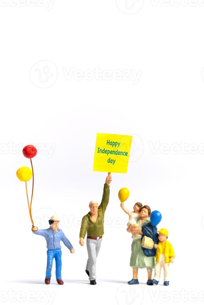 Miniature people holding flags with word Happy Independence day photo
