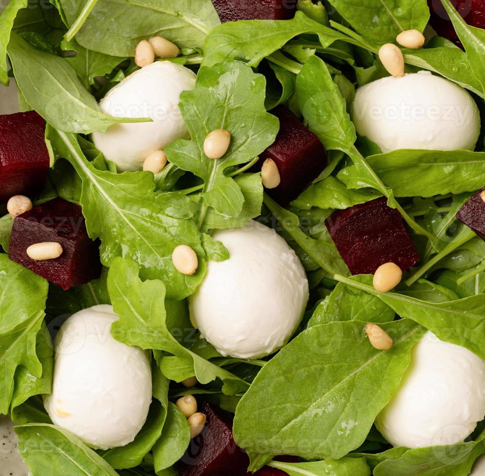 Beetroot, mozzarella and arugula salad with pine nuts top view photo