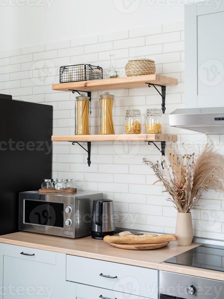 Interior of kitchen in rustic style with vintage kitchen ware and wooden wall. White furniture and wooden decor in bright cottage indoor. photo