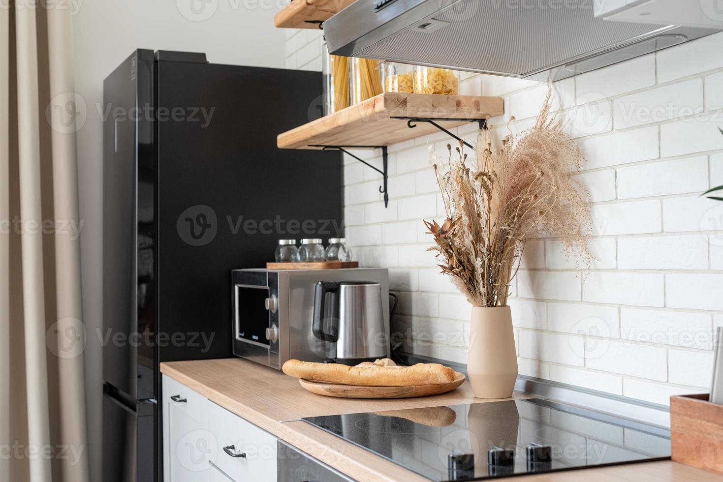 Interior of kitchen in rustic style with vintage kitchen ware and wooden wall. White furniture and wooden decor in bright cottage indoor. photo