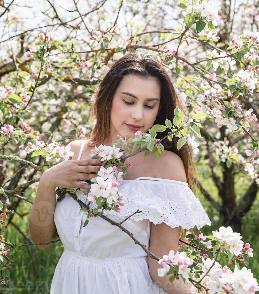 Young caucasian woman enjoying the flowering of an apple trees photo