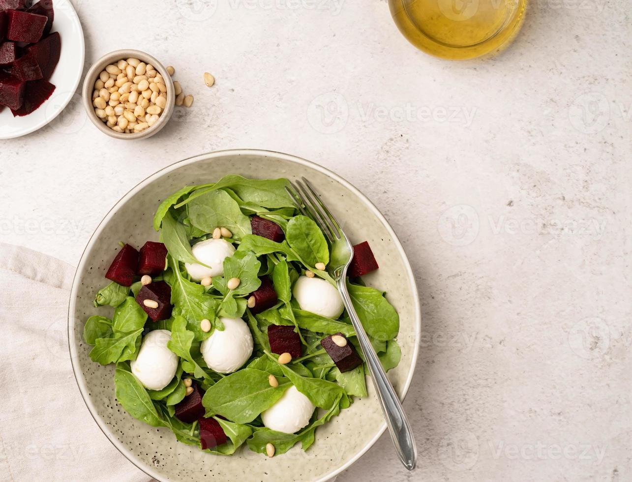 Beetroot, mozzarella and arugula salad with pine nuts top view photo