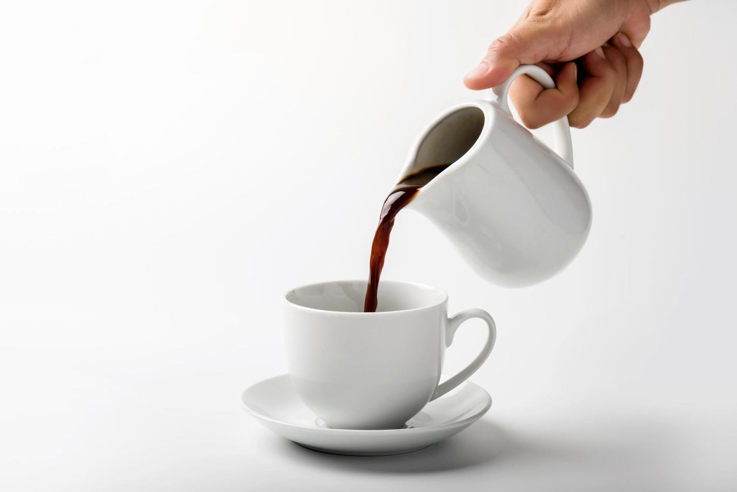 pouring a cup of coffee over white background photo