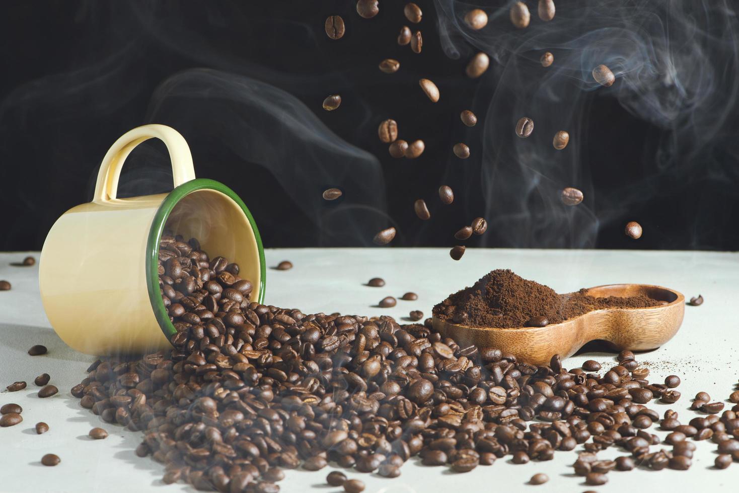 Taza de café y frijoles y café molido en un recipiente de madera sobre un fondo blanco. foto