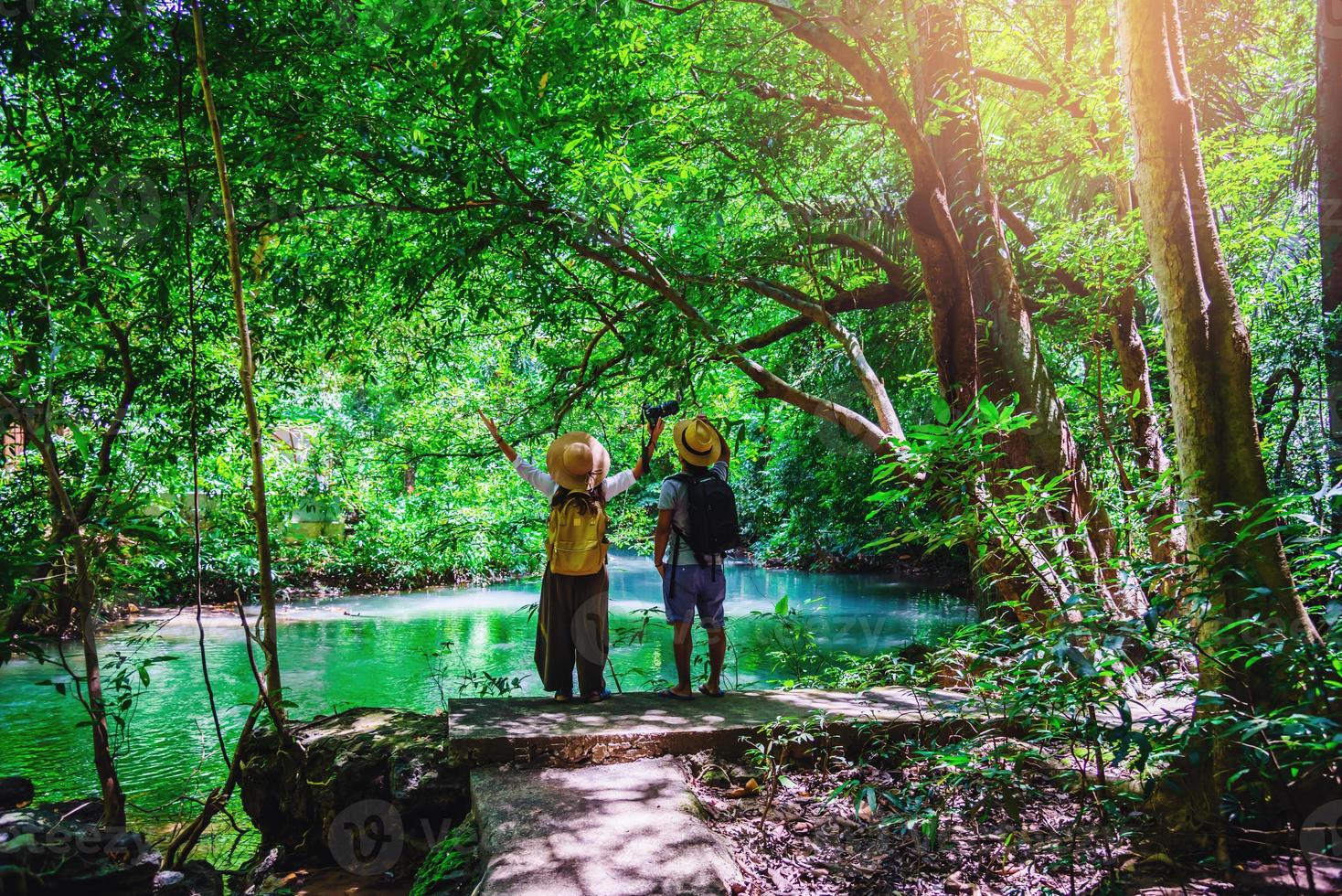 viajeros, parejas con mochilas de viaje naturales durante las vacaciones. parejas viajando, relajándose en la jungla verde y disfrutando del hermoso estanque esmeralda. turismo, senderismo, estudio de la naturaleza. foto