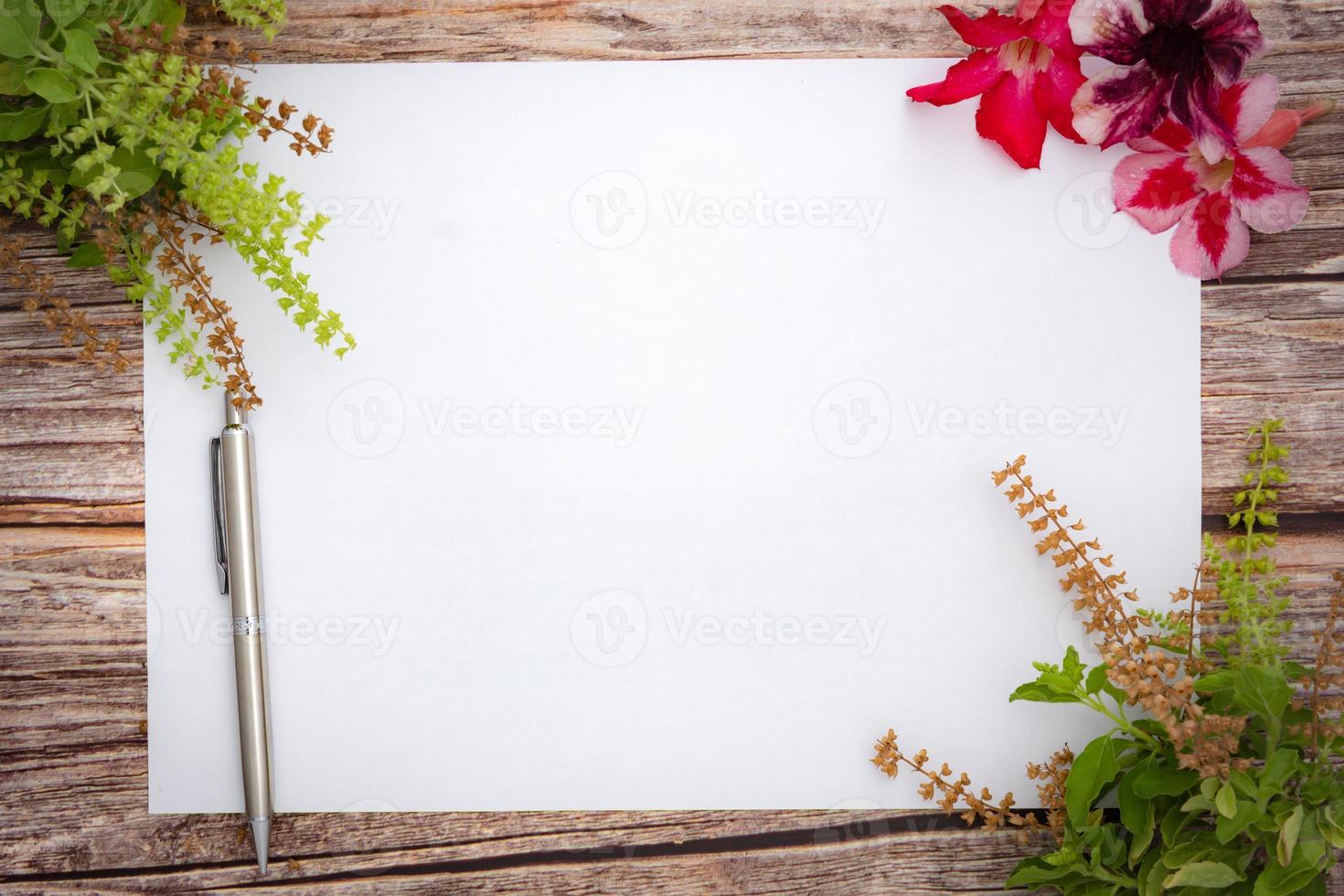 Conceptual space for text, which consists of blank paper, azalea, basil flowers,and pens on a wooden background.Blank template for your text.top view.flat lay photo