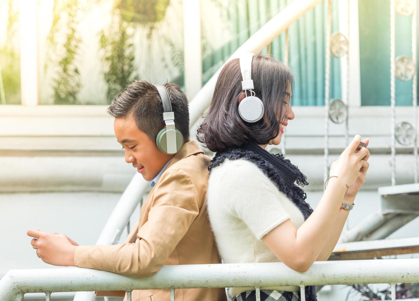 Young boy and girl play games and listen to music on their mobile phones photo