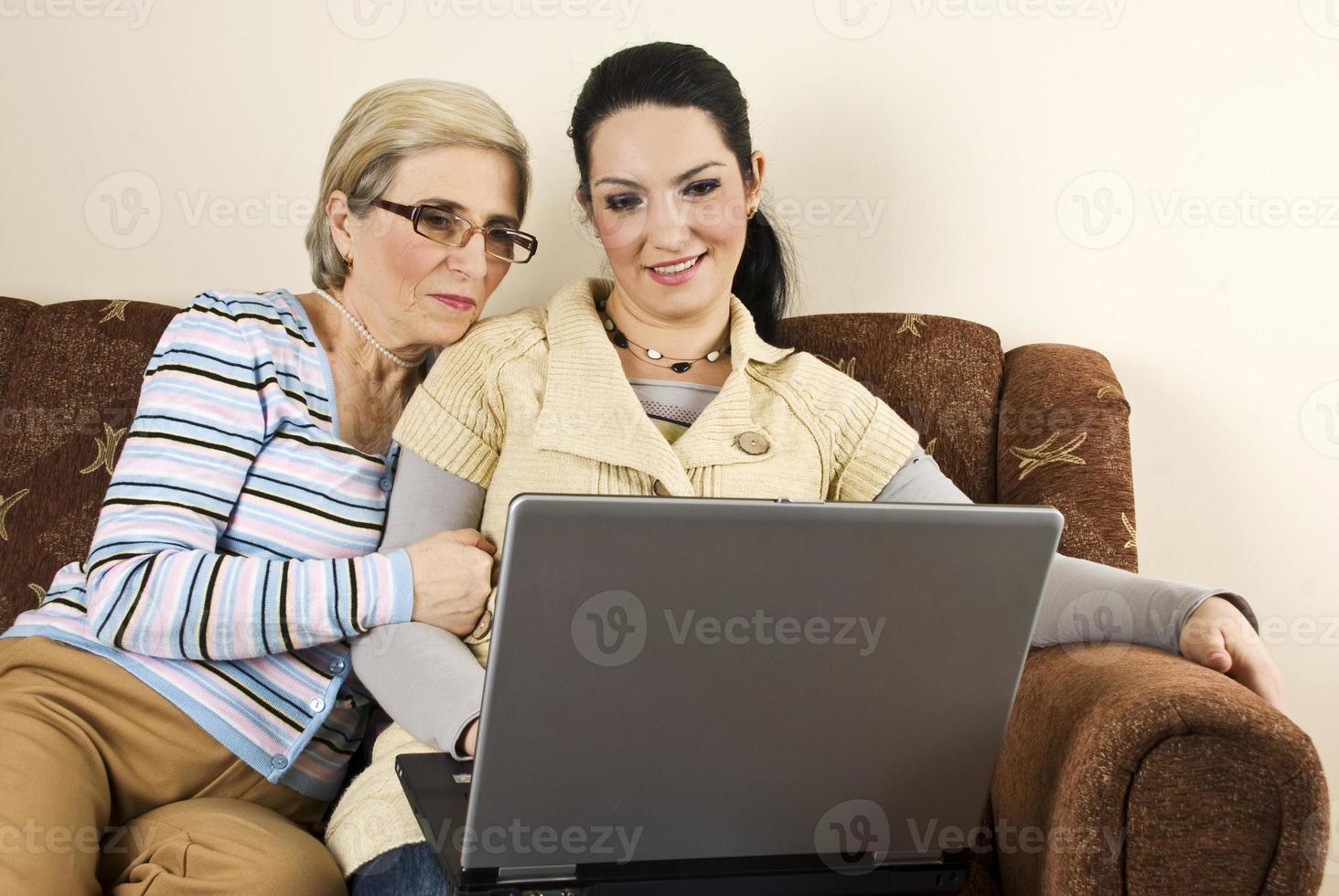 Smiling two women with laptop home photo
