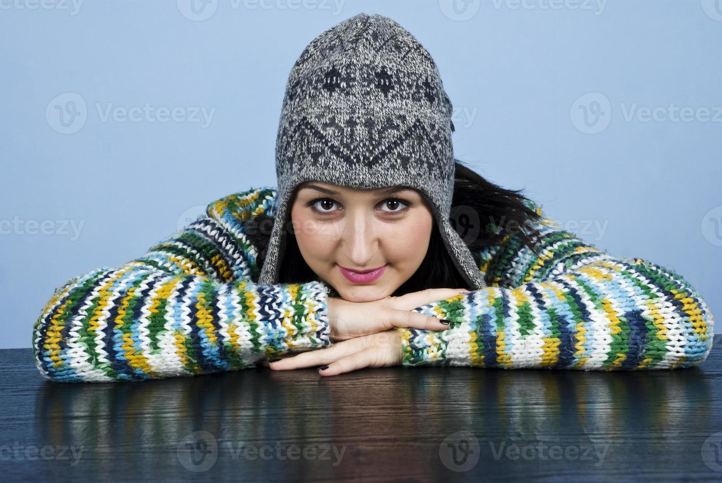 Girl in wool cap sit with head on table photo