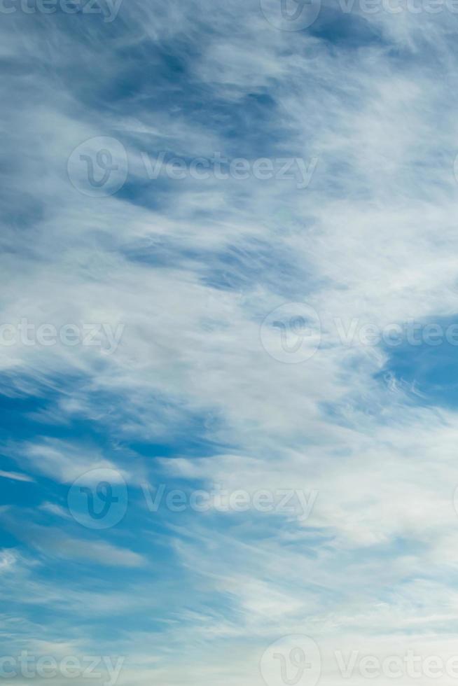 Blue sky background. Light cirrus clouds in rays of  sun on summer day. photo