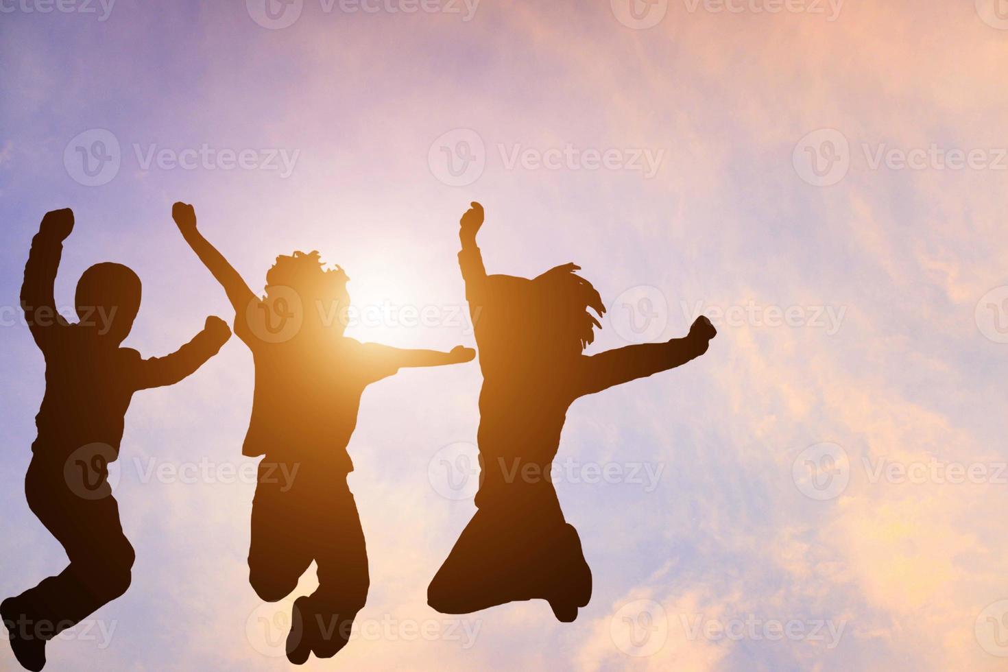 portrait silhouette group of people jumping on orange sky happily to successful work. photo