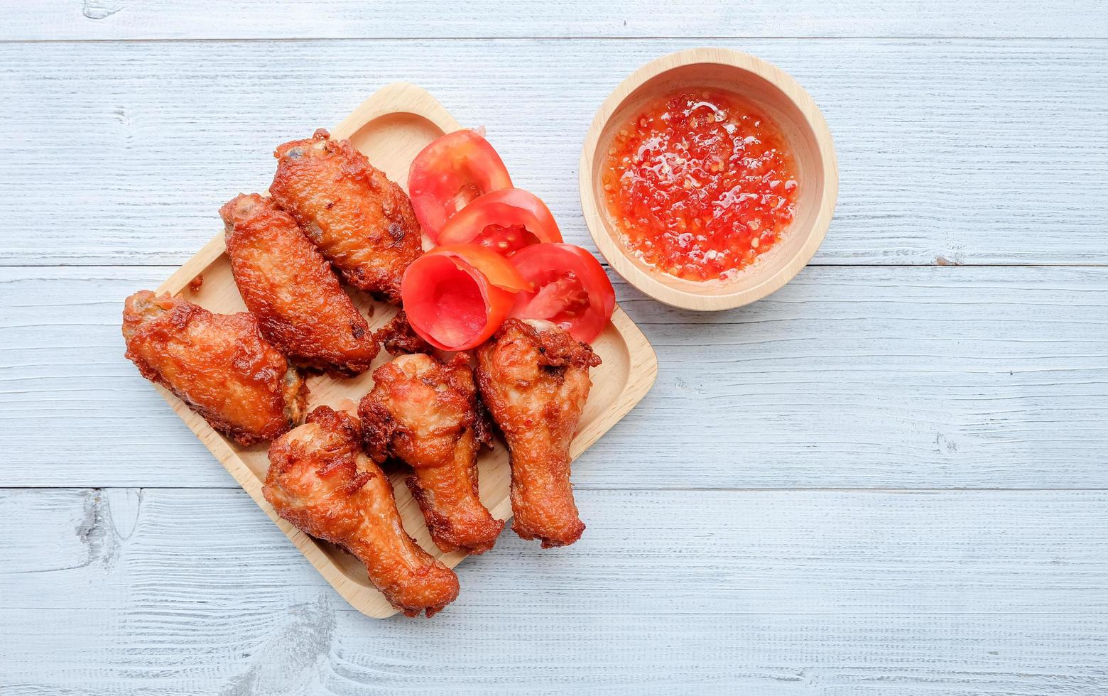 vista superior y primer plano de ala de pollo frito en plato blanco con salsa dulce sobre fondo de madera. comida popular para niños. foto