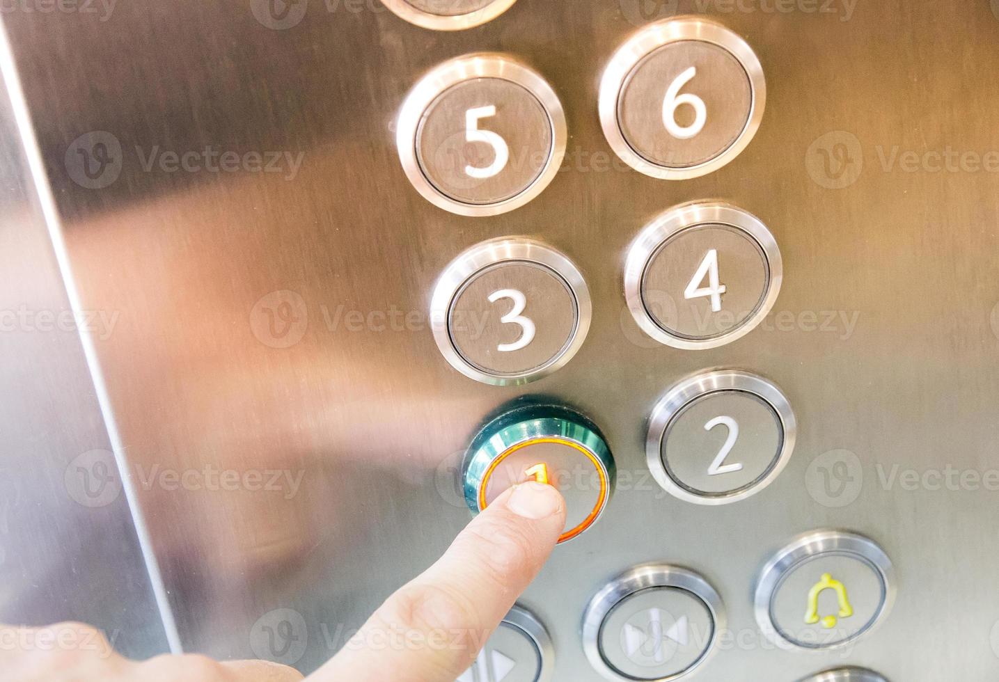 Man's hand causes first floor in metal elevator photo
