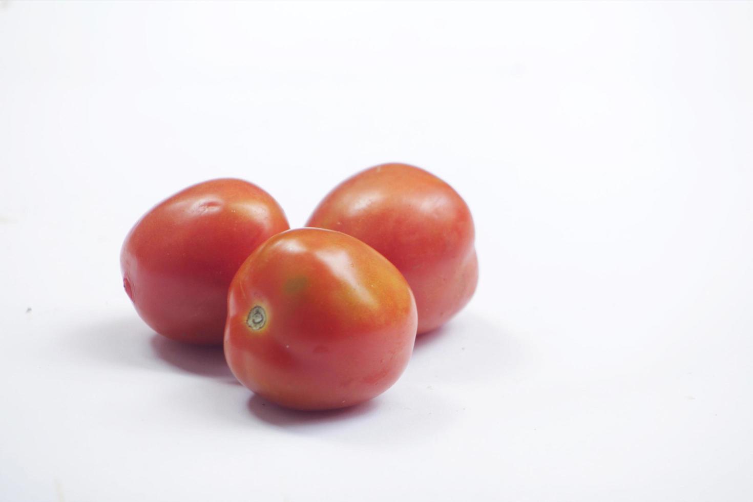 three red orange tomatoes on a white background photo