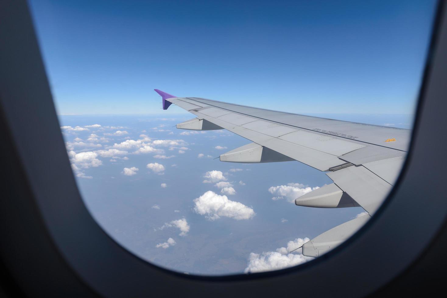 Wing of the plane flying above the clouds. View from the window of an airplane photo