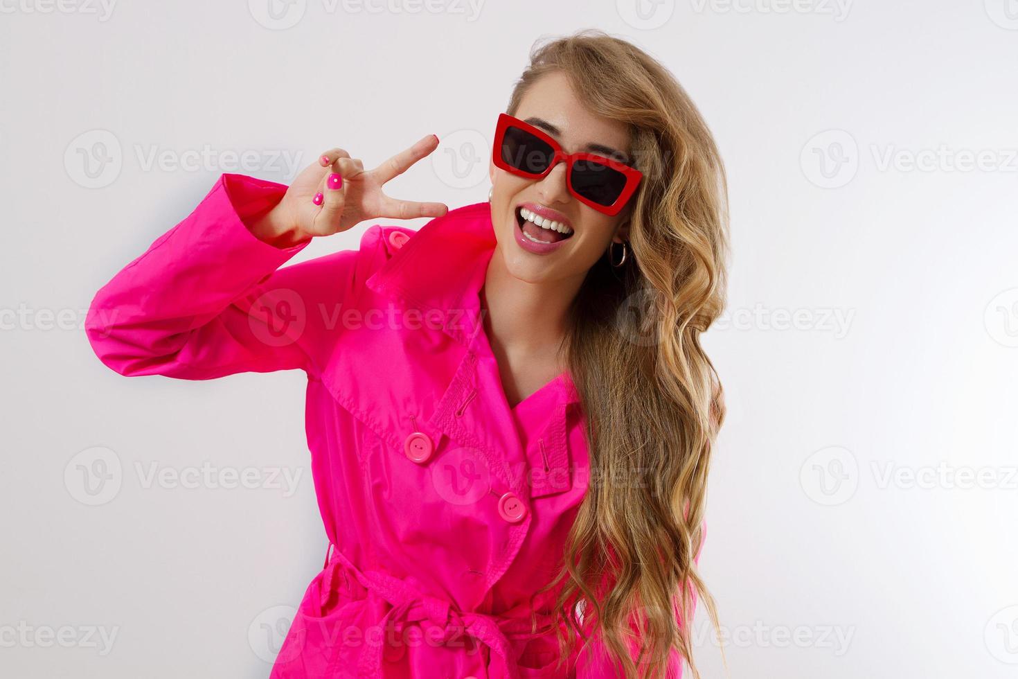 Happy, shock, excited woman face closeup. Peace sign. Girl bright pink autumn clothes, red sunglasses isolated. white background, copy space. Beautiful female surprised cheerful. funny model screaming photo