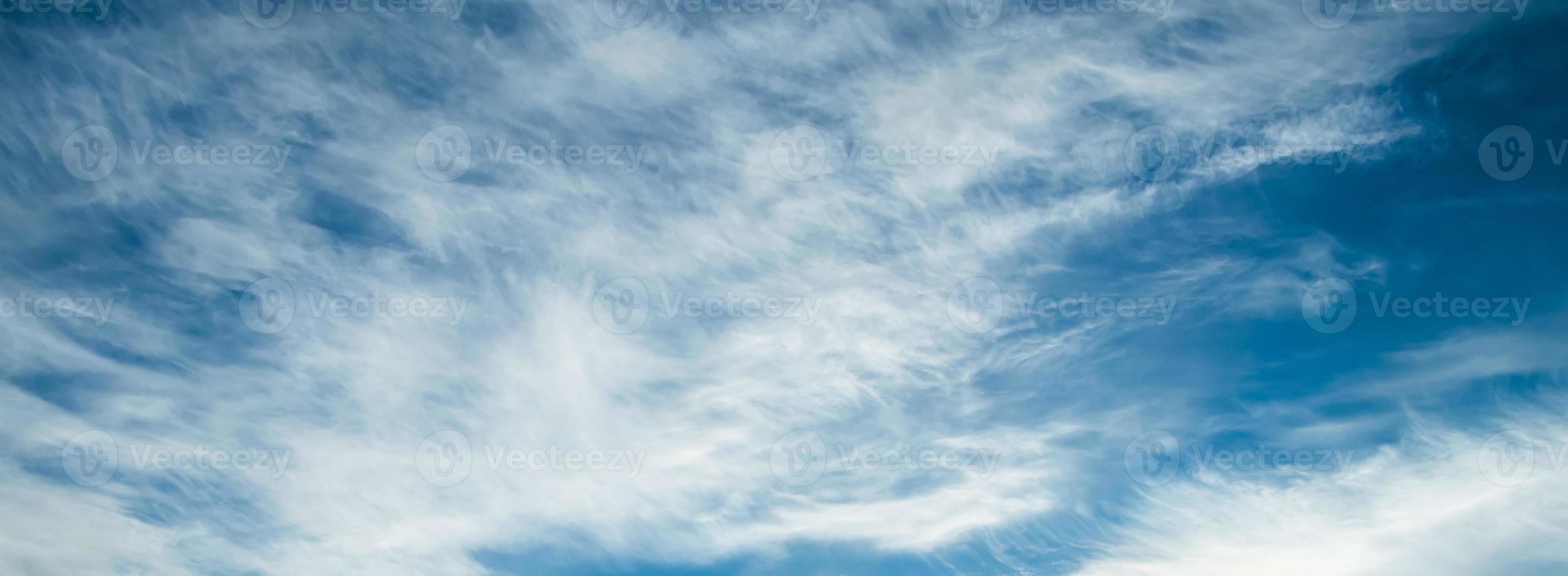 Blue sky background. Light cirrus clouds in rays of  sun on summer day. photo