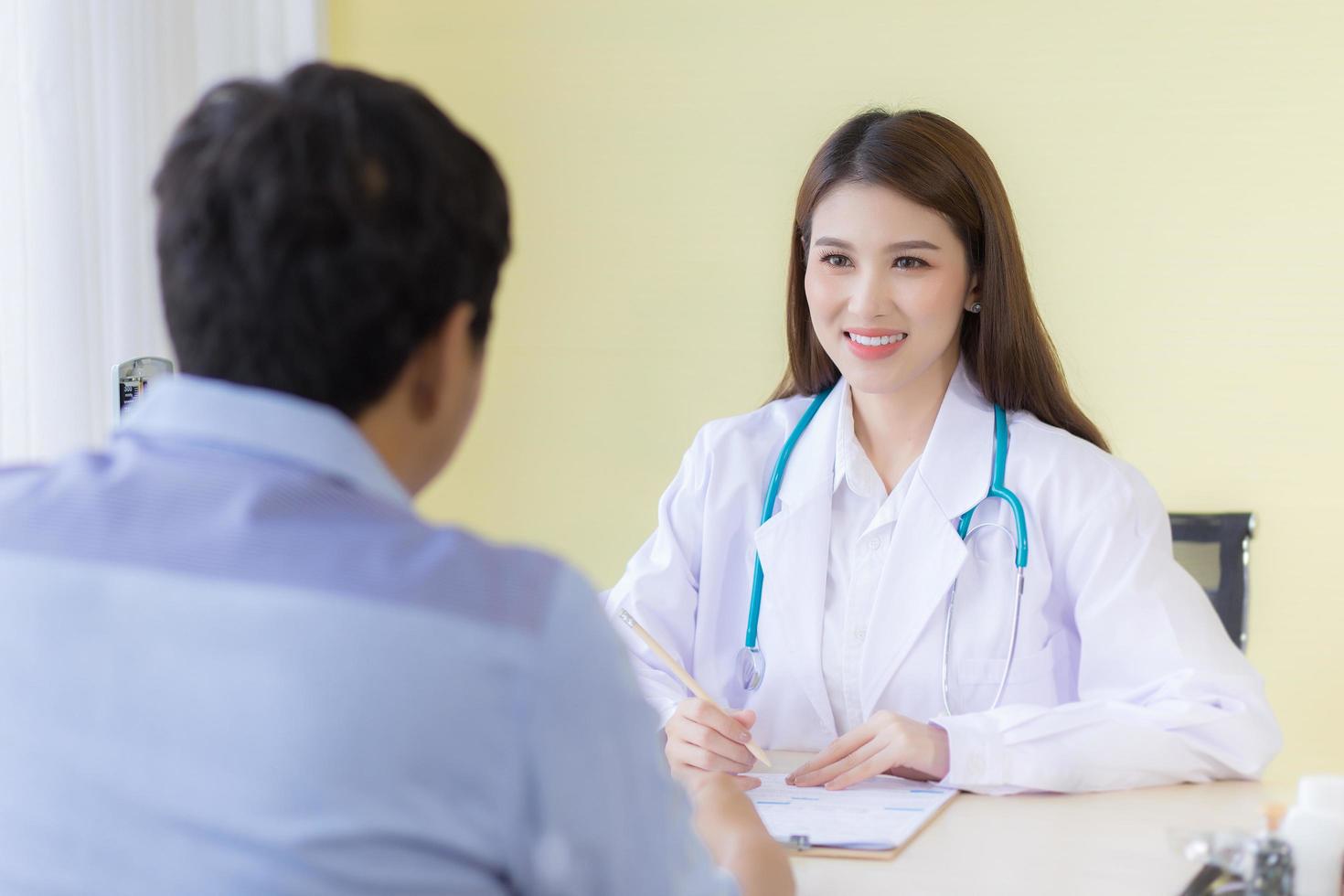 A beautiful Asian female doctor smiled and asked about the symptoms. photo