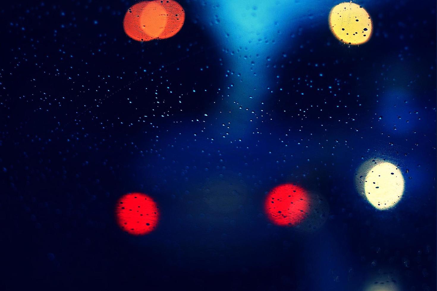 Rain drops on car glass and colorful traffic bokeh light photo