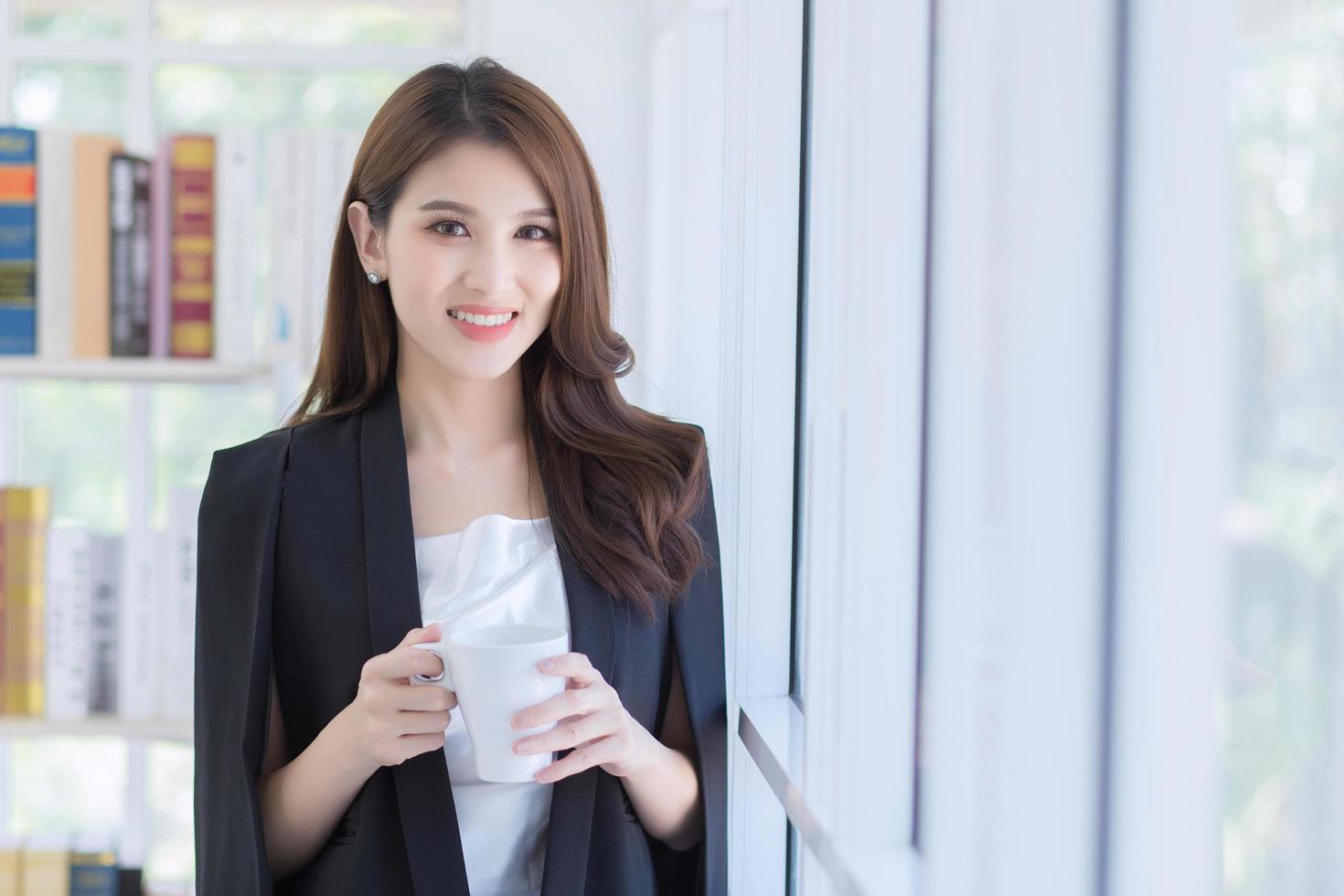 An office girl standing in a cup of coffee By the window. photo