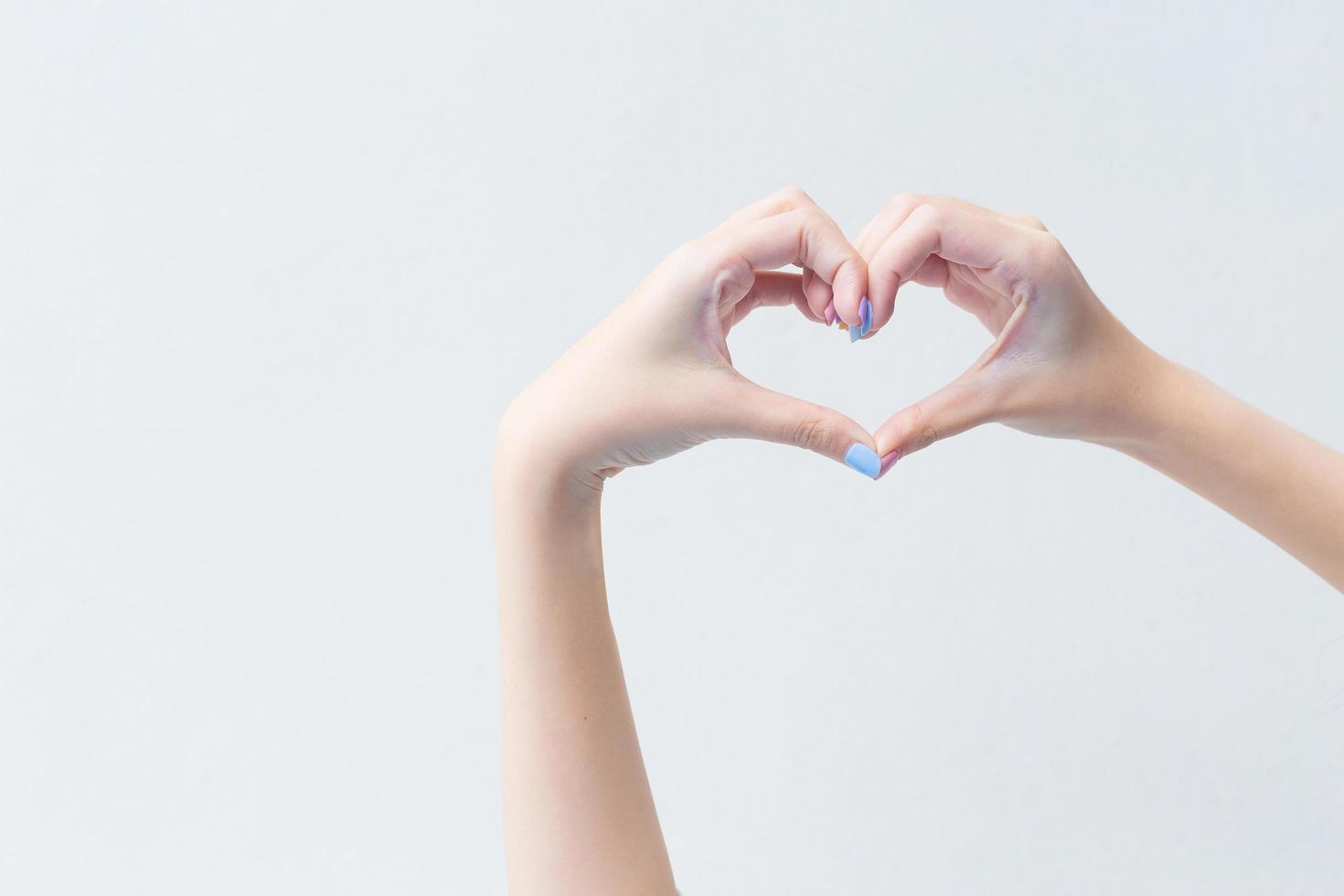 Beautiful female hand shows heart symbol as love sign in manicure concept. photo