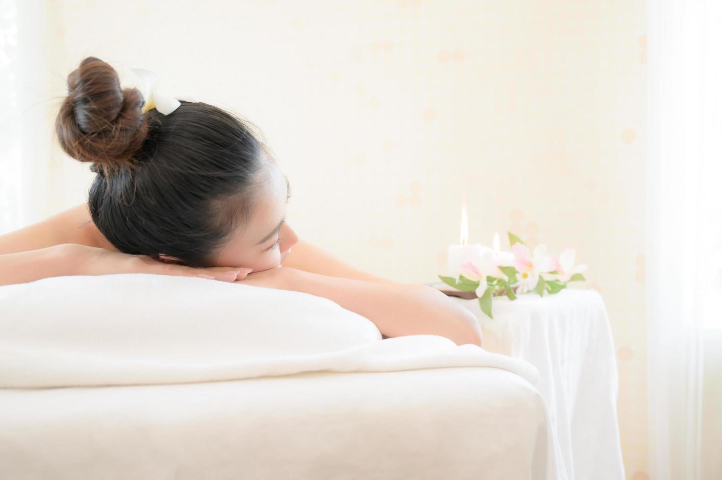 una hermosa mujer asiática está cómodamente relajada y duerme en una tienda de spa después de que la masajista haya masajeado su cuerpo foto