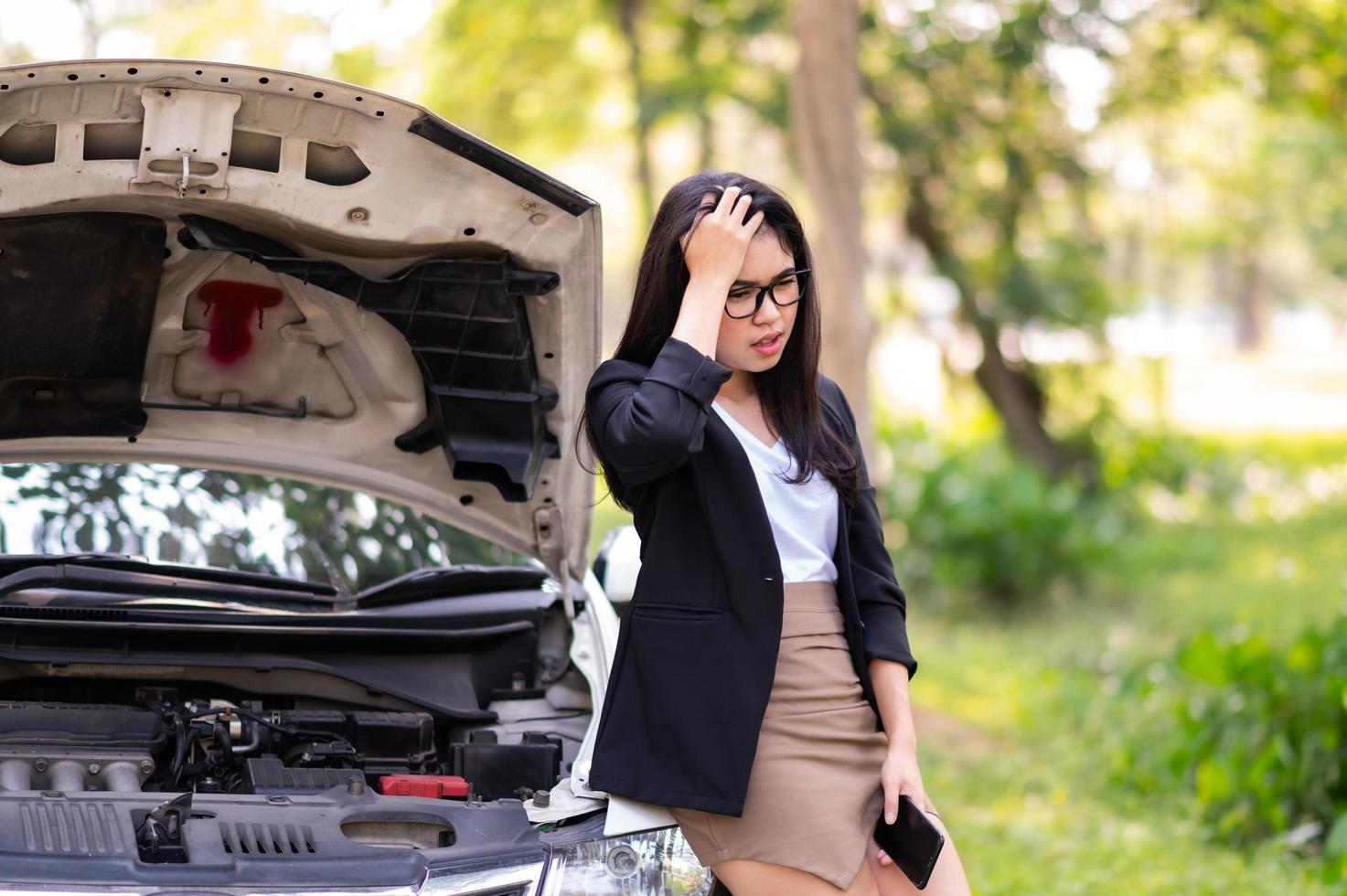 una mujer asiática está estresada mientras espera que un técnico repare un camión dañado al costado de la carretera foto