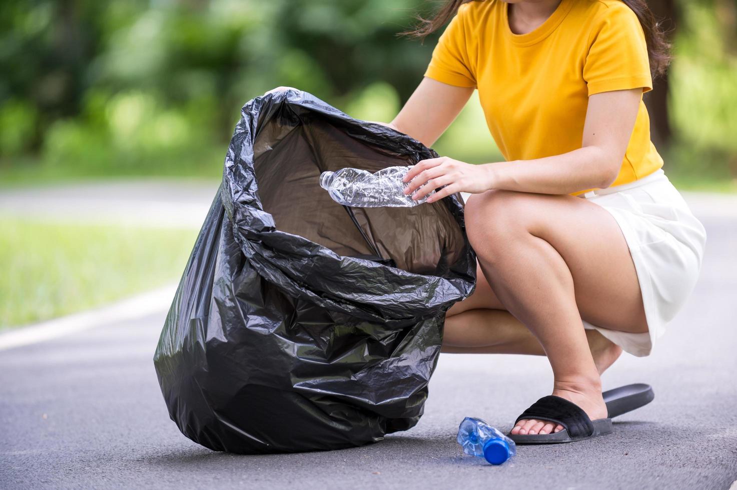 Volunteer women collect plastic water bottles in the park area photo