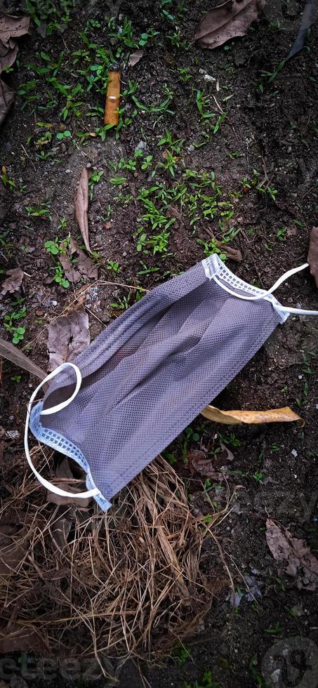 An unused-disposable grey face mask thrown away on the ground. photo