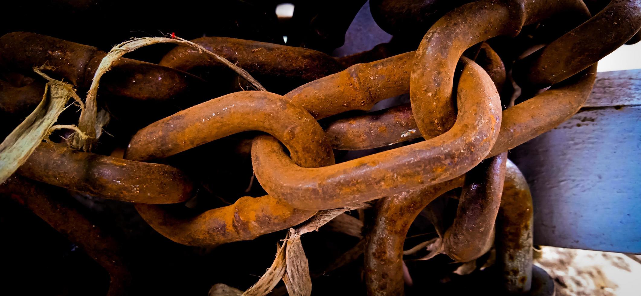 Yellow corroded iron chain wrapped around on the iron pole. photo