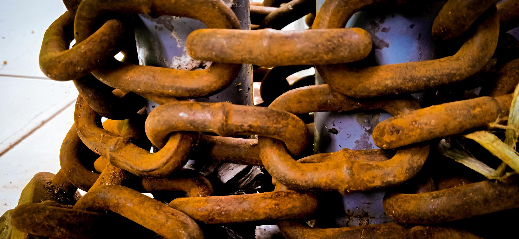 Yellow corroded iron chain wrapped around on the iron pole. photo