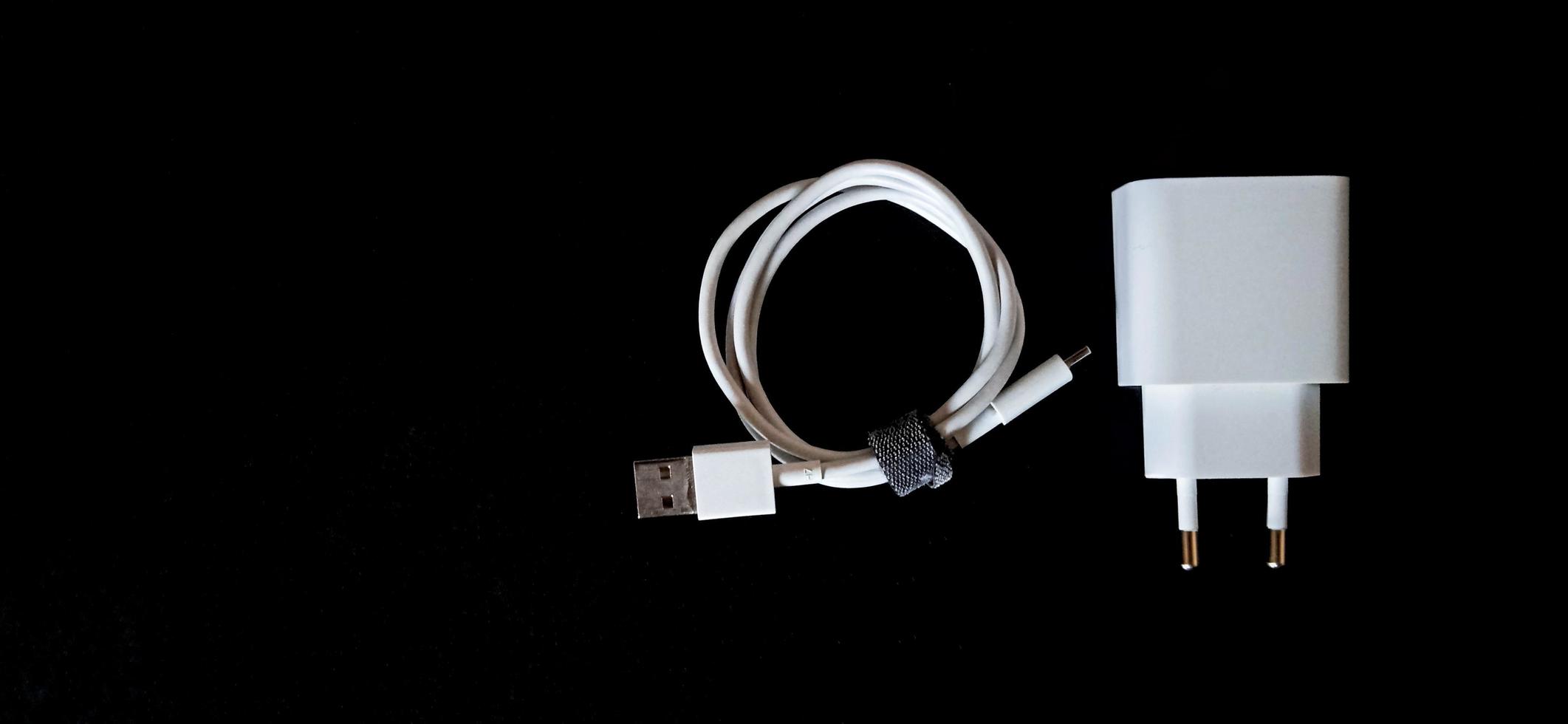 White smartphone charger on the black background. Smartphone charging electronic device. photo