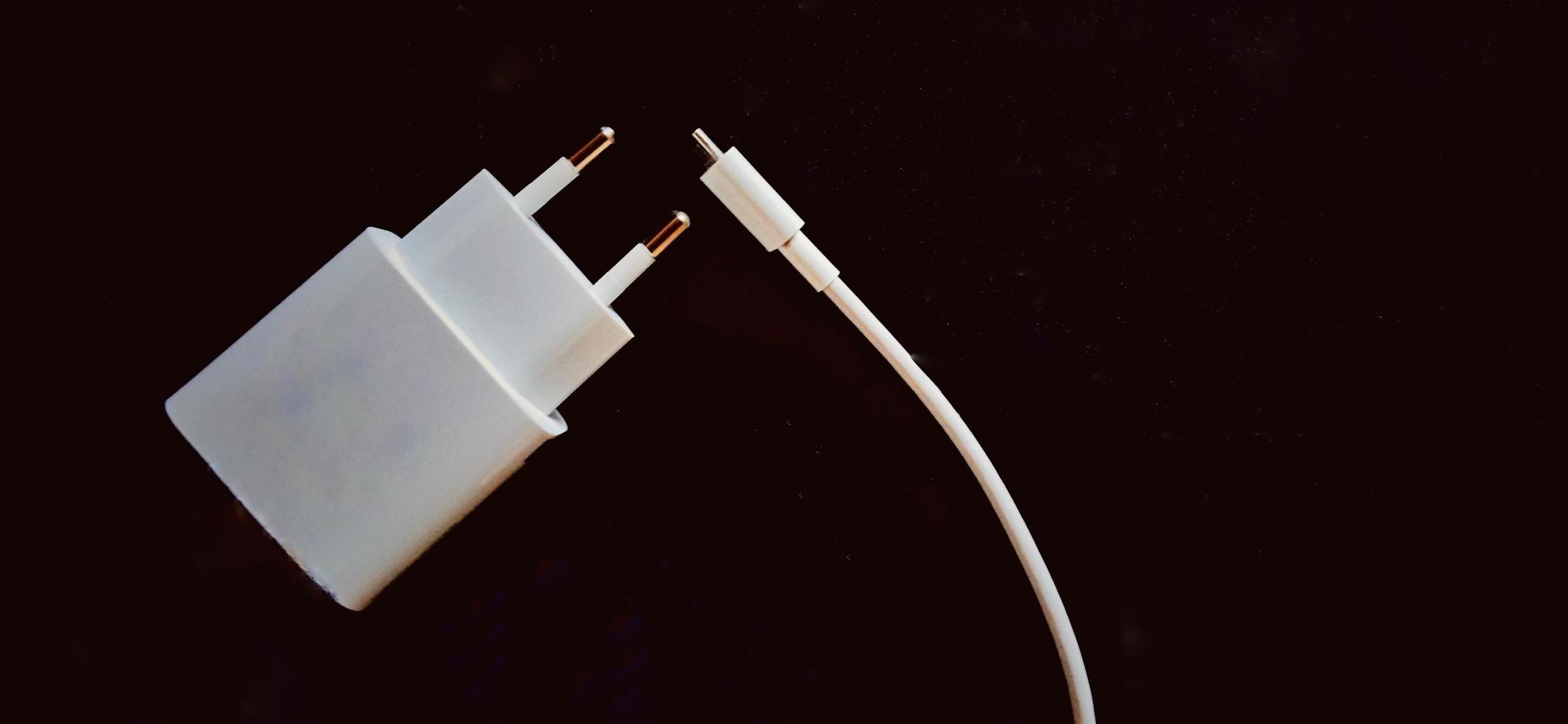 White smartphone charger on the black background. Smartphone charging electronic device. photo