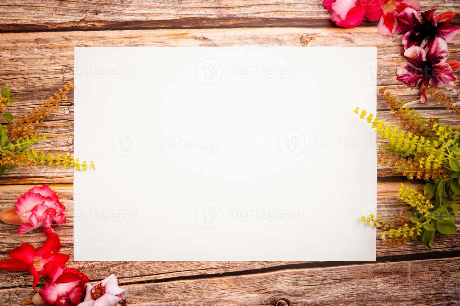 Pink azalea flowers with green basil flowers and blank paper sheet on a wooden background.spring border pink and green blossom, top view. Blank template for your text. flat lay. photo