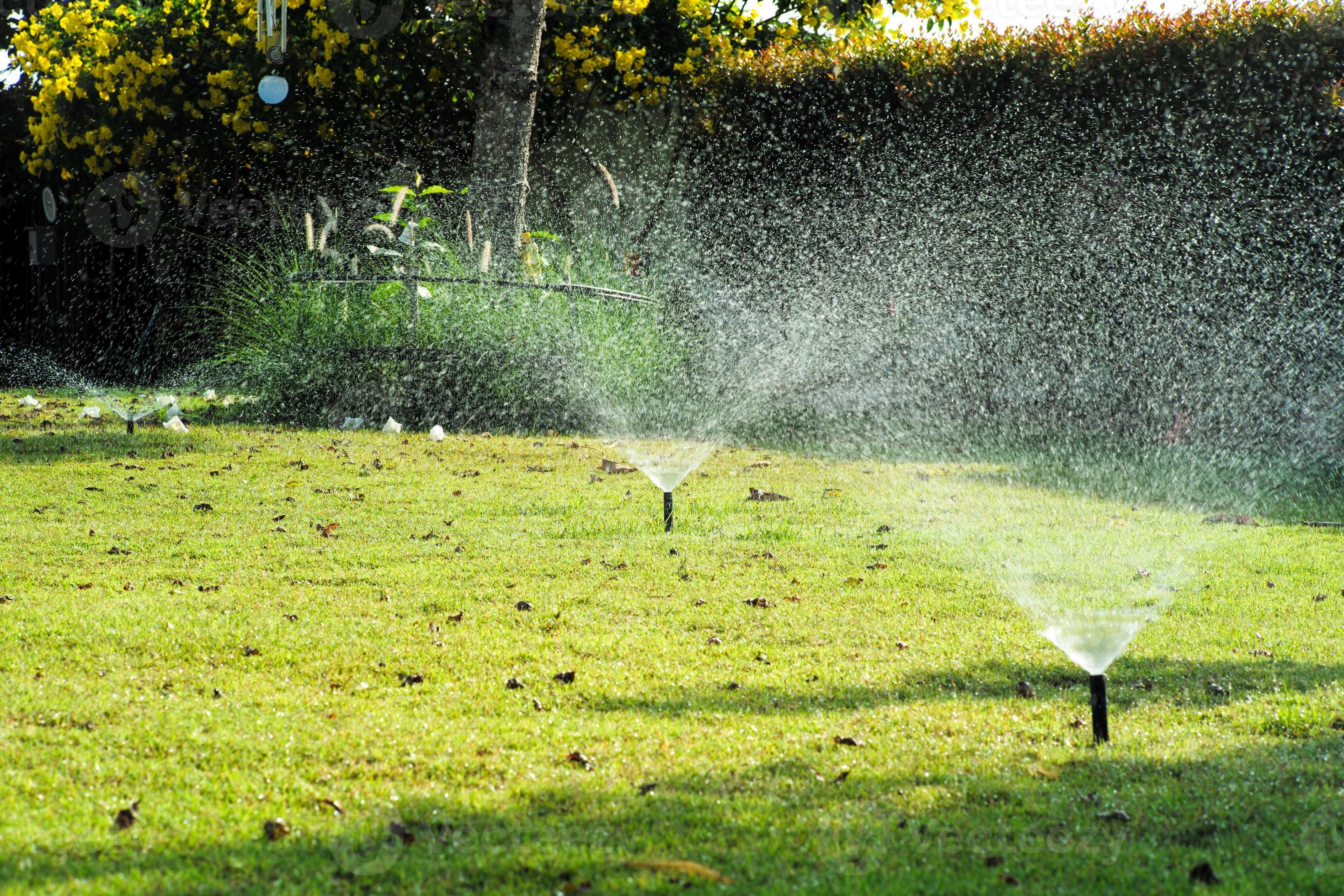 Selective focus on the sprinkle watering around the grass field with