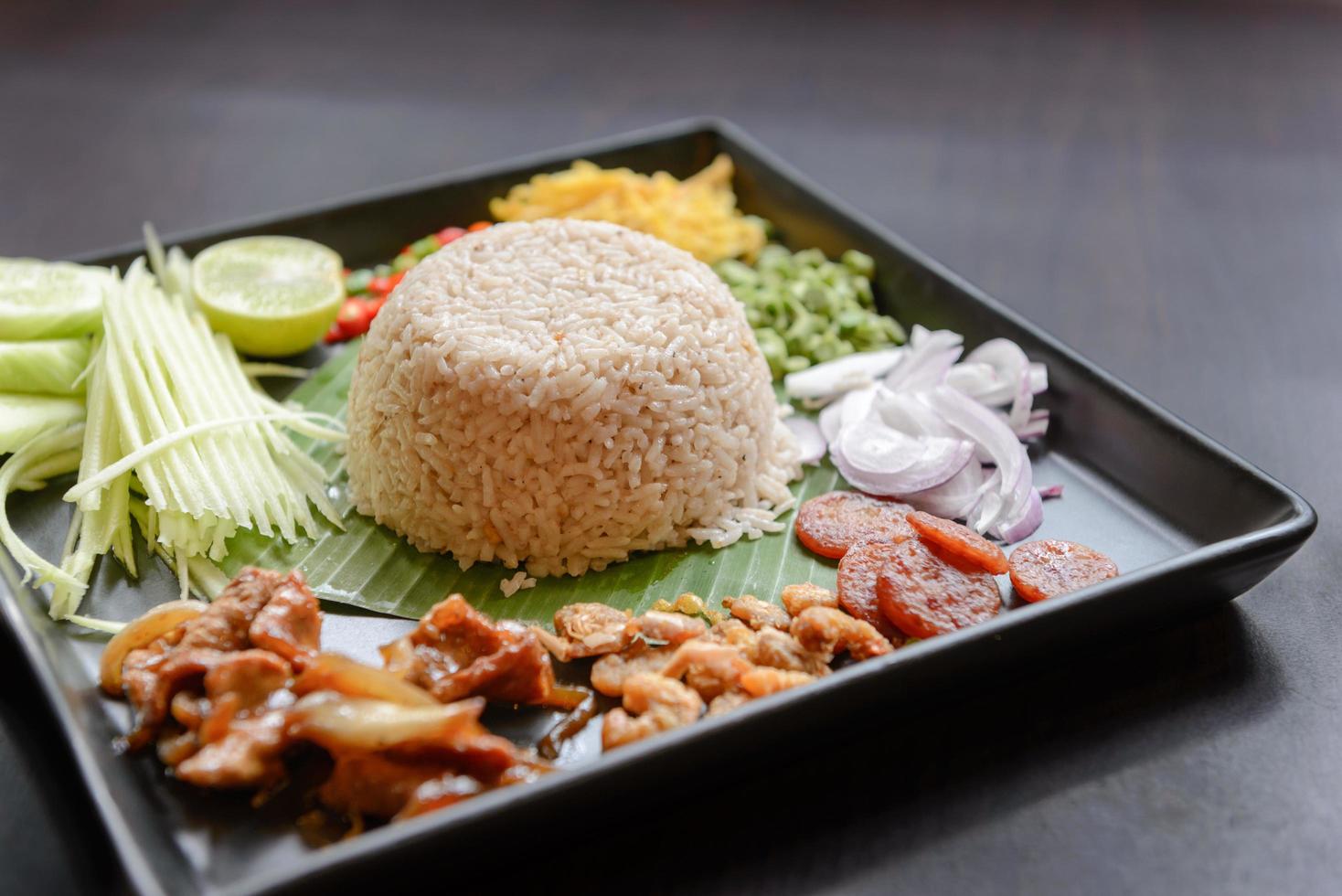 Thai food - Rice mixed with shrimp paste, Kao Cluk Ka Pi with side dish as a mango, lemon, chili, cucumber, scrambled egg, cow-pea, shallots, Chinese sausage, dried shrimp and pork photo