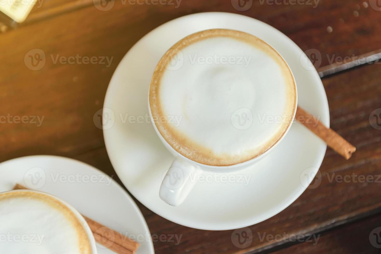 vista superior de la taza de capuchino de café caliente con espuma de leche en la mesa de madera foto