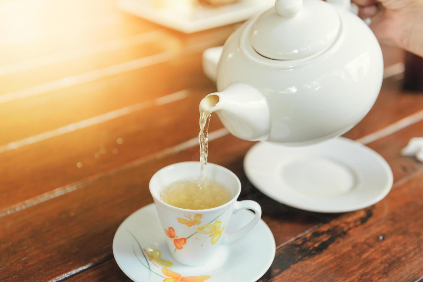 hora de la pausa del té. el té se vierte de la tetera en una taza. foto