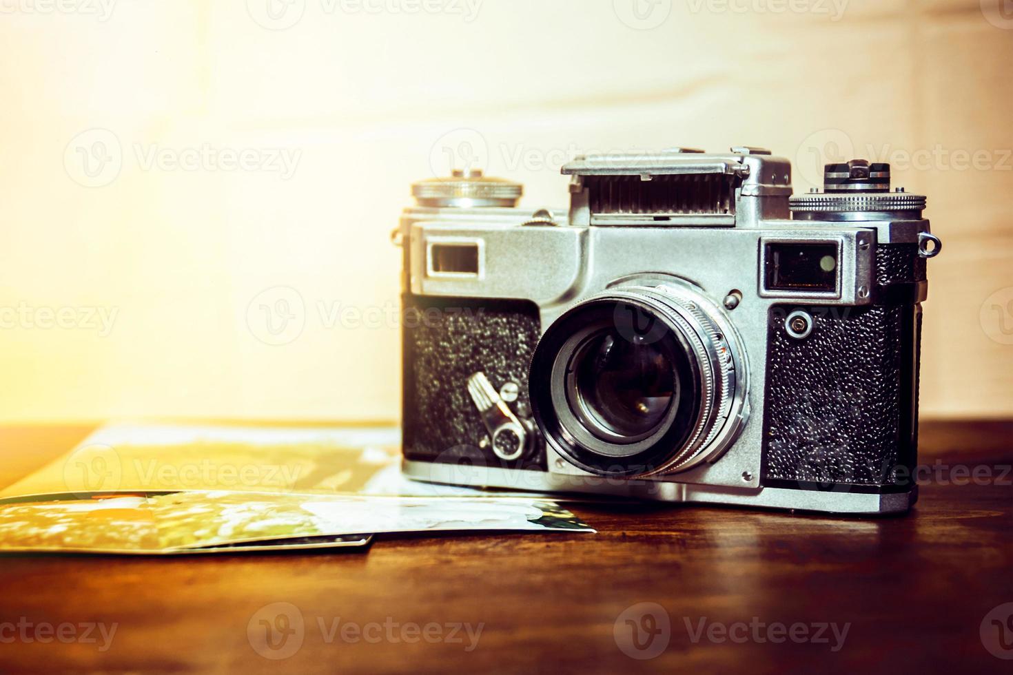 old camera is on the table on a stack of photos