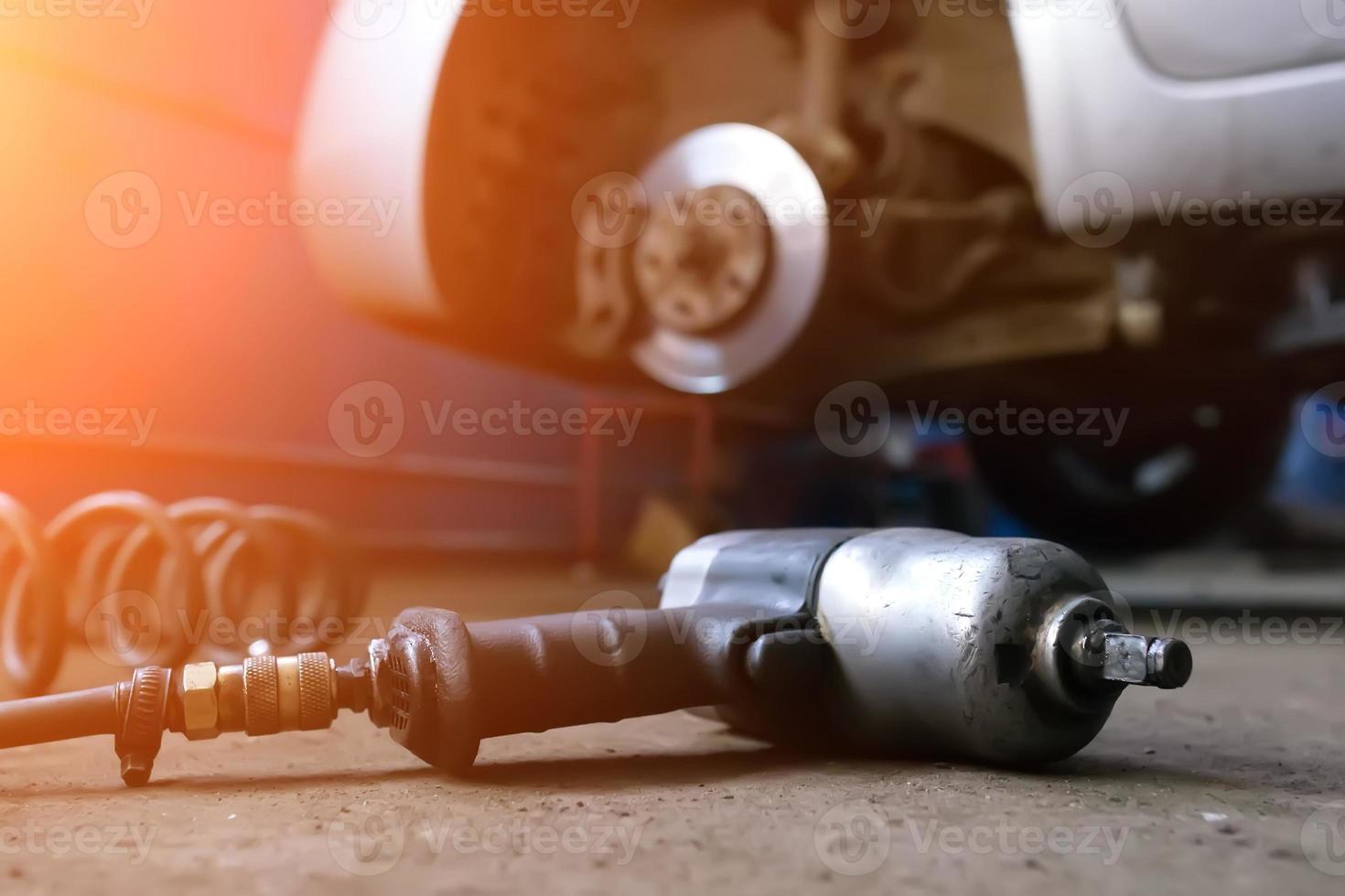 Auto mechanic man with electric screwdriver changing tire outside. Car service. Hands replace tires on wheels. Tire installation concept. photo