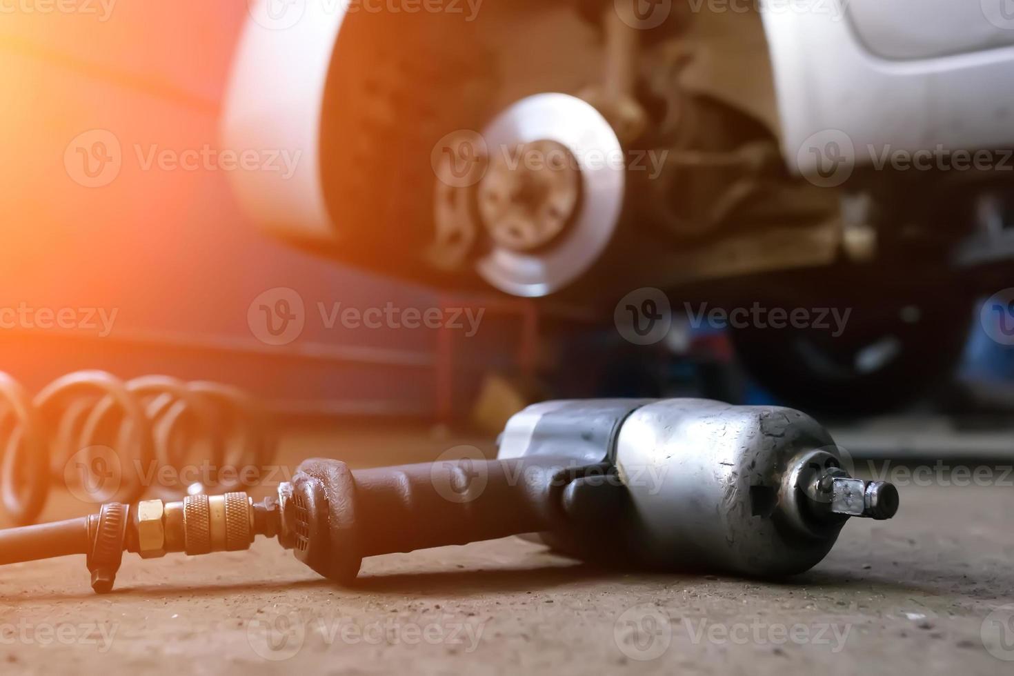 hombre mecánico de automóviles con destornillador eléctrico cambiando neumáticos afuera. Servicio de auto. las manos reemplazan los neumáticos en las ruedas. concepto de instalación de neumáticos. foto