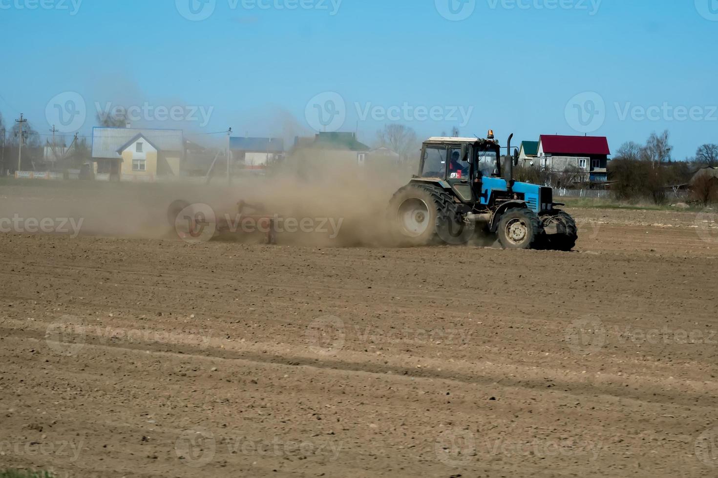 agricultor en tractor preparando tierra con cultivador de semillero como parte de las actividades previas a la siembra a principios de la temporada de primavera de trabajos agrícolas en tierras de cultivo. foto