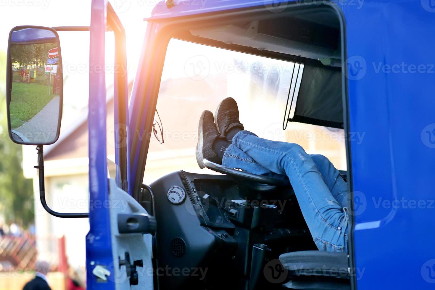 el conductor del camión descansa en la cabina del camión con los pies en el volante foto