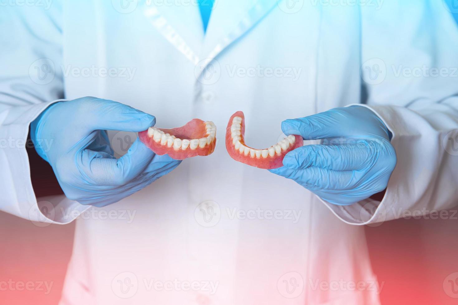 Dental prosthesis in the hands of the doctor close-up. Dentist holding ceramic dental bridge. Front view of complete denture. Dentistry conceptual photo. Prosthetic dentistry. photo