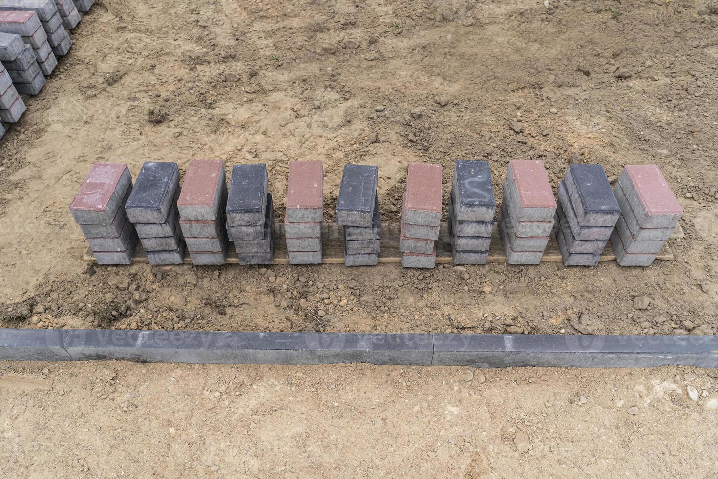 Laying of gray concrete paving slabs in the house courtyard driveway patio. Professional working masons install new tiles or slabs for the driveway, sidewalk or patio on a flat sandy foundation. photo