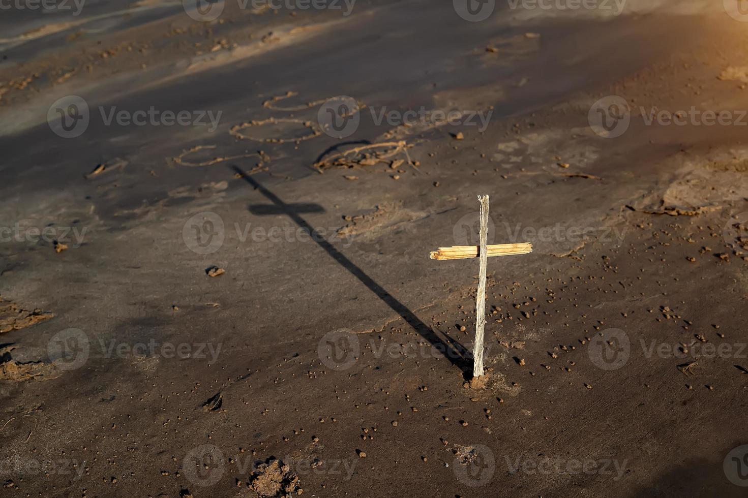 wooden Christian cross on the beach, behind the inscription SOS photo