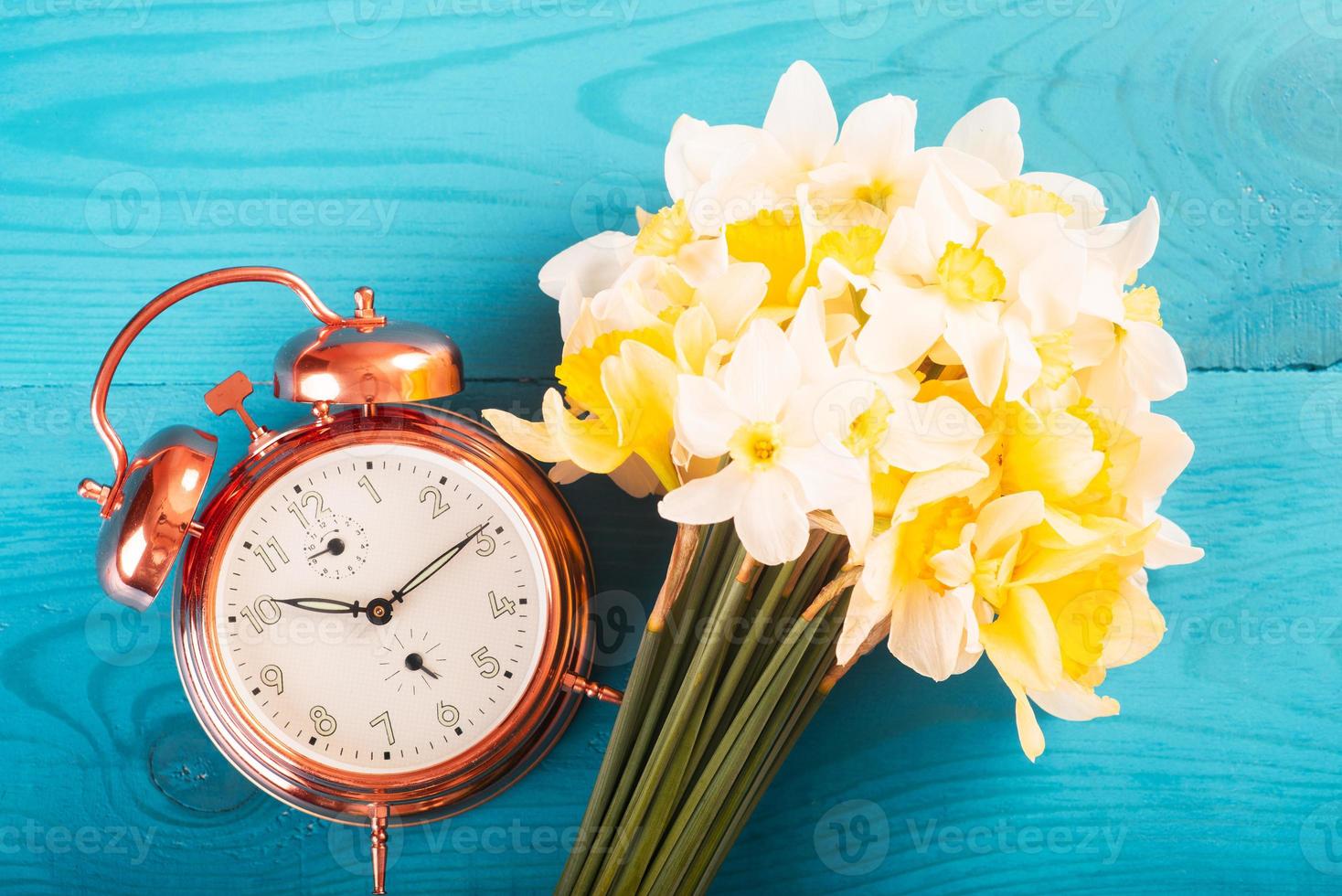 Vintage mechanical alarm clock with yellow daffodils on a blue wooden background. Good morning, we are from Ukraine photo