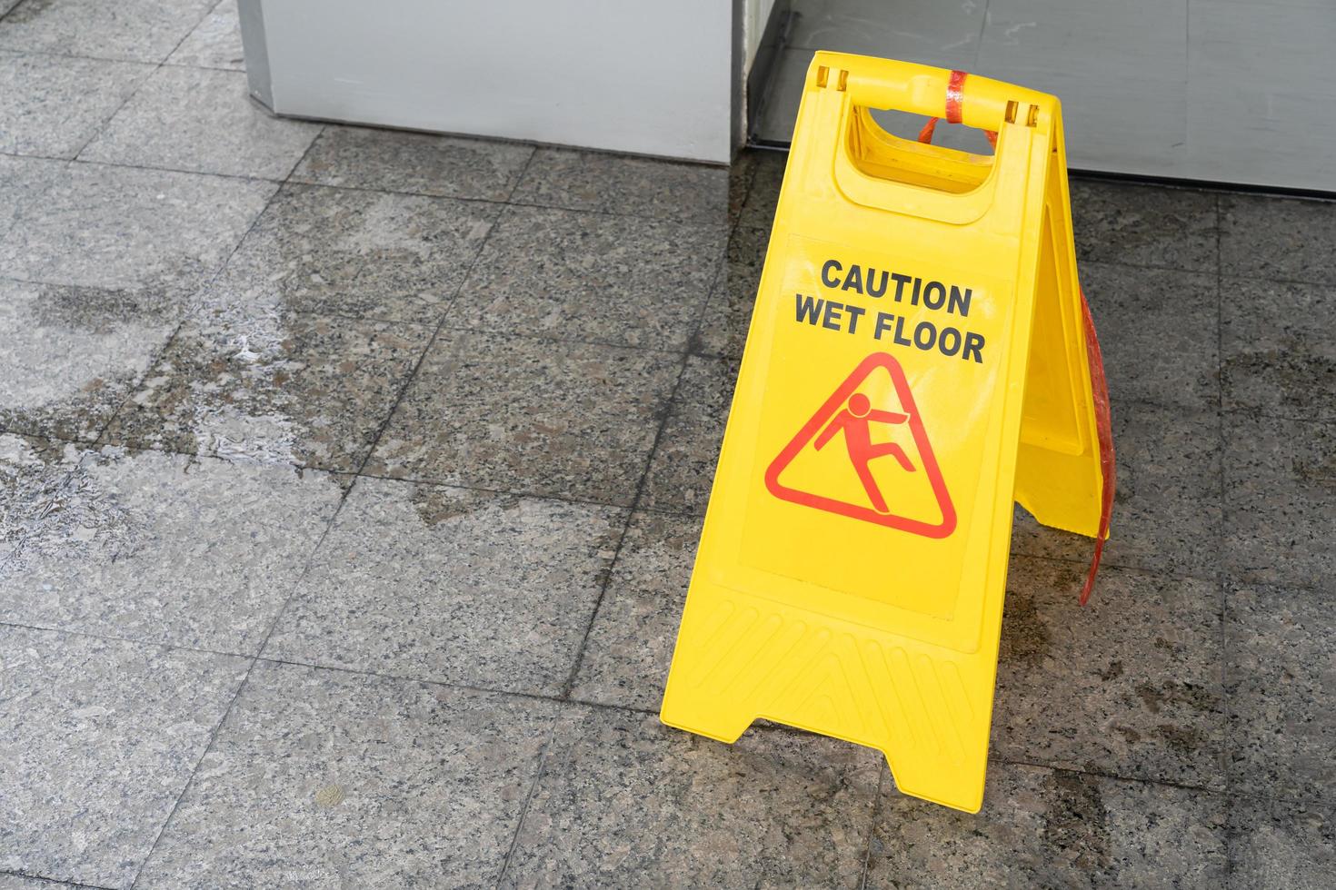 Yellow Caution slippery wet floor sign on the wet ground photo